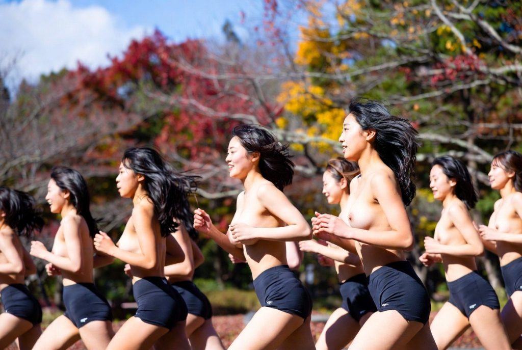 深霞学園大学における体育授業。女子学生が上半身裸で自然の中を走っている。
